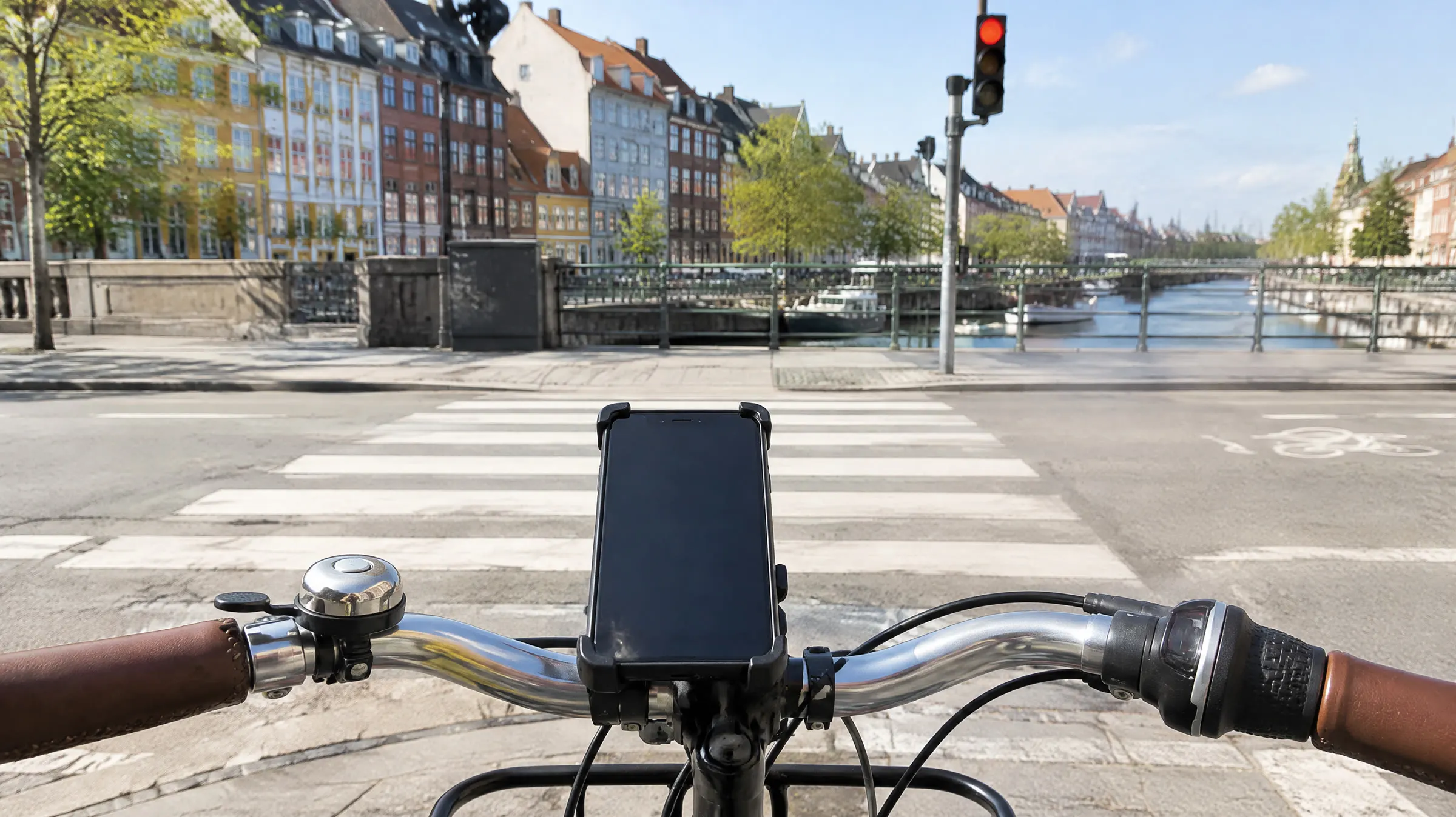 En mobil i en holder på cykelstyret ved et fodgængerfelt i København, skærmen er slukket